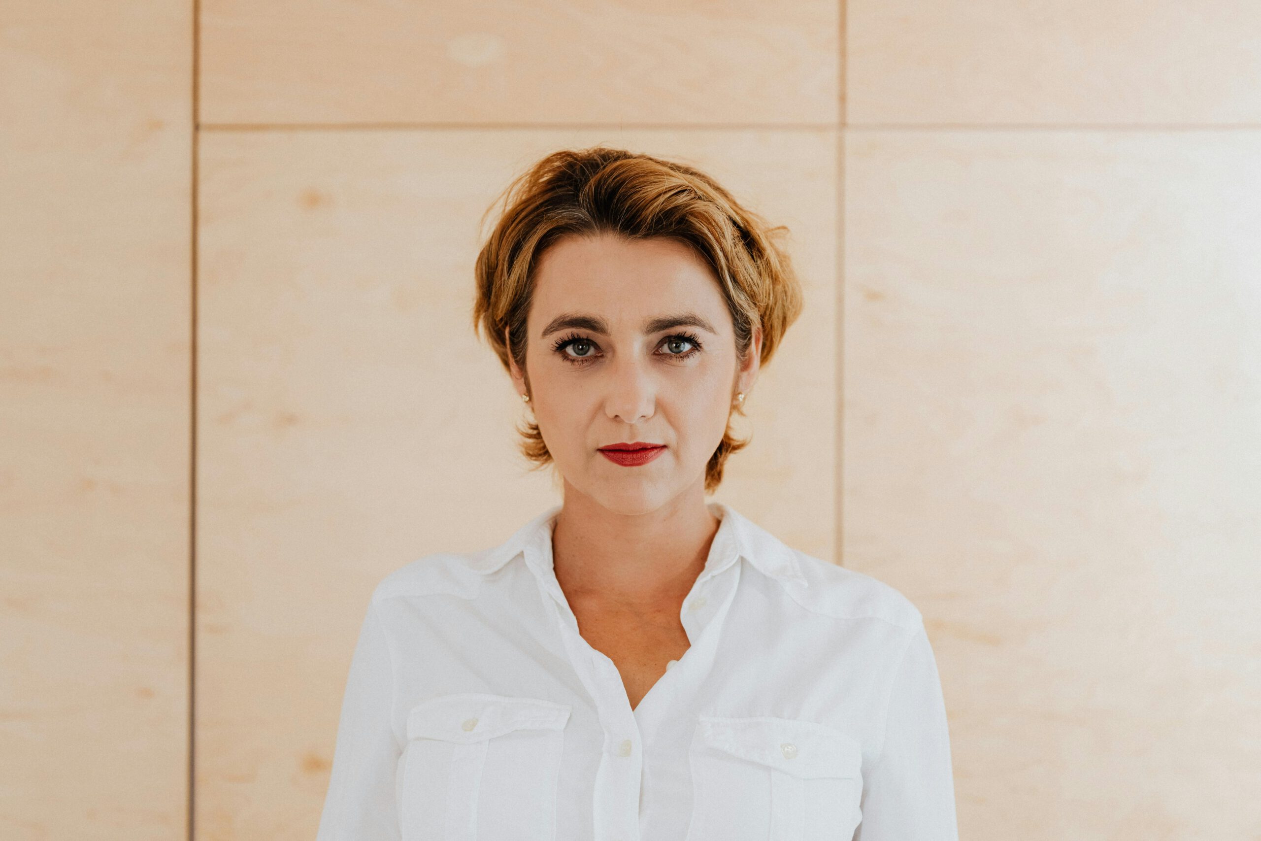 Portrait of a confident businesswoman wearing a white shirt standing against a wooden background.